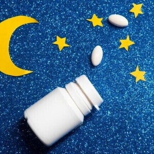 Frasco branco de comprimidos aberto com pílulas espalhadas sobre fundo azul com brilho, decorado com estrelas e uma lua amarela de papel. Frasco branco de comprimidos aberto com pílulas espalhadas sobre fundo azul com brilho, decorado com estrelas e uma lua amarela de papel.