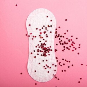 Absorvente sobreposto com várias estrelinhas vermelhas, sob um fundo rosa