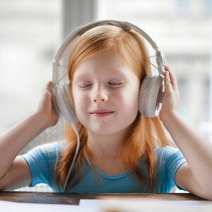 Uma menina de olhos fechados, usando fones de ouvido e sorrindo levemente, com as mãos próximas aos fones. Uma menina de olhos fechados, usando fones de ouvido e sorrindo levemente, com as mãos próximas aos fones.