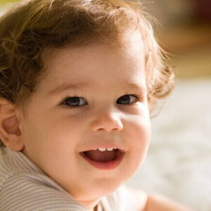 Bebê deitado e sorrindo, sendo iluminado pela luz do sol