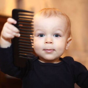Um bebê segurando um pente de cabelo.