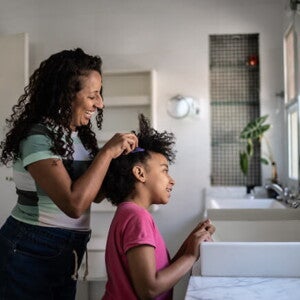 mulher faz tranças no cabelo de criança mulher faz tranças no cabelo de criança