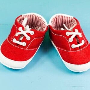Par de sapatos de bebezinho vermelho, sobre um fundo azul.