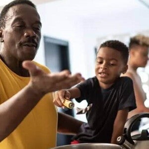 ser pai Pai e filho cozinham juntos como uma homenagem de dia dos pais. O pai está mexendo uma panela e o filho, ao seu lado, o ajuda.