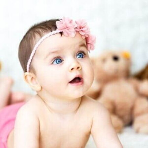 Um bebê deitado com a boca aberta, com ursos de pelúcia ao fundo.