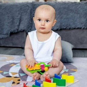 Um bebê sentado, com objetos lúdicos colocados à sua frente. Um bebê sentado, com objetos lúdicos colocados à sua frente.