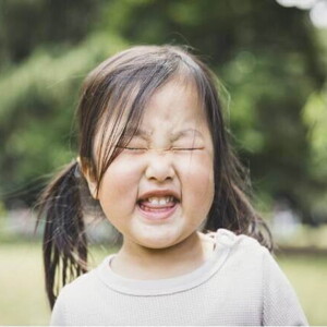 A foto destaca o rosto de uma menina fazendo caretas. A imagem remete ao tema de tique em crianças
