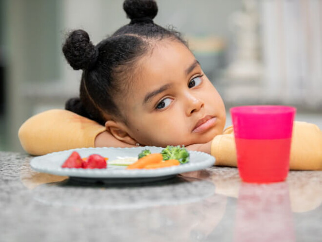 menina com semblante desconfiado olha para prato de comida sem vontade menina com semblante desconfiado olha para prato de comida sem vontade