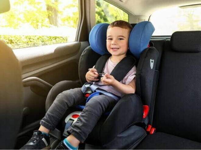 Um menino, sentado em um assento de elevação no carro, sorrindo e parecendo confortável. Um menino, sentado em um assento de elevação no carro, sorrindo e parecendo confortável.