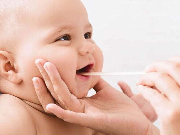 Bebê sendo examinado com palito abaixador de língua