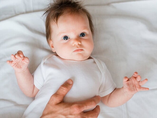 Bebê deitado em uma cama recebendo cuidados de uma profissional de saúde Bebê deitado em uma cama recebendo cuidados de uma profissional de saúde