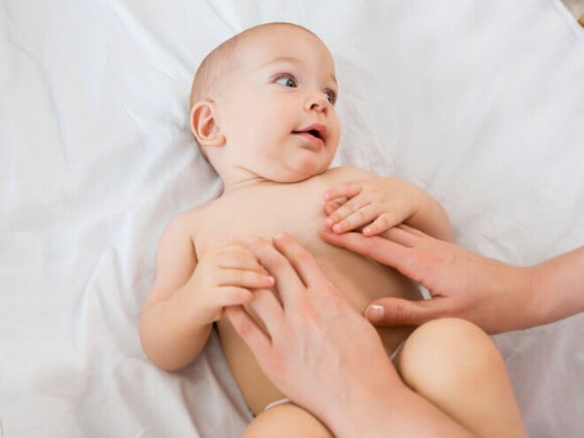 bebê usando fralda e um adulto com as mãos sob a barriga do bebê bebê usando fralda e um adulto com as mãos sob a barriga do bebê
