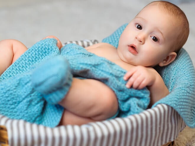 Imagem de um bebê aconchegado em um cobertor azul dentro de uma cesta Imagem de um bebê aconchegado em um cobertor azul dentro de uma cesta
