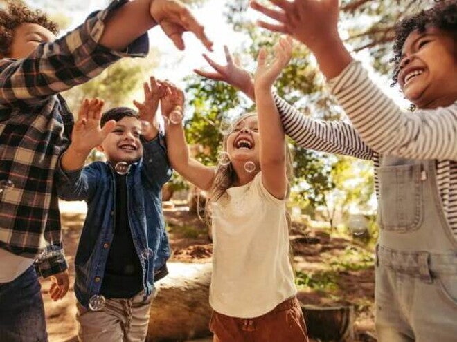 Crianças sorridentes num parque, brincando ao ar livre com bolhas de sabão Crianças sorridentes num parque, brincando ao ar livre com bolhas de sabão