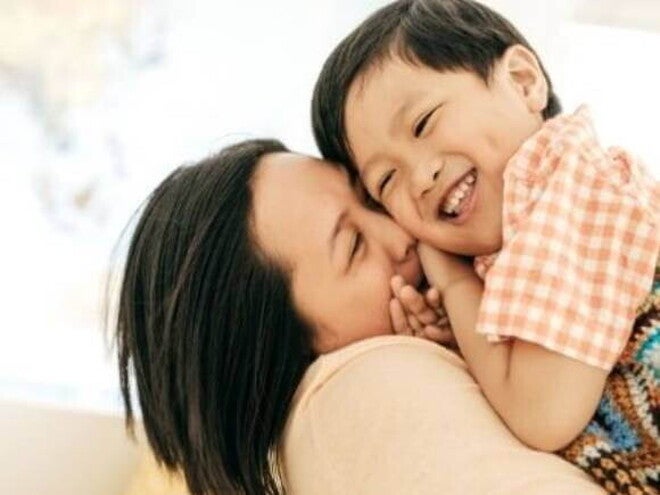 Uma mãe segurando o filho nos braços e sorrindo.