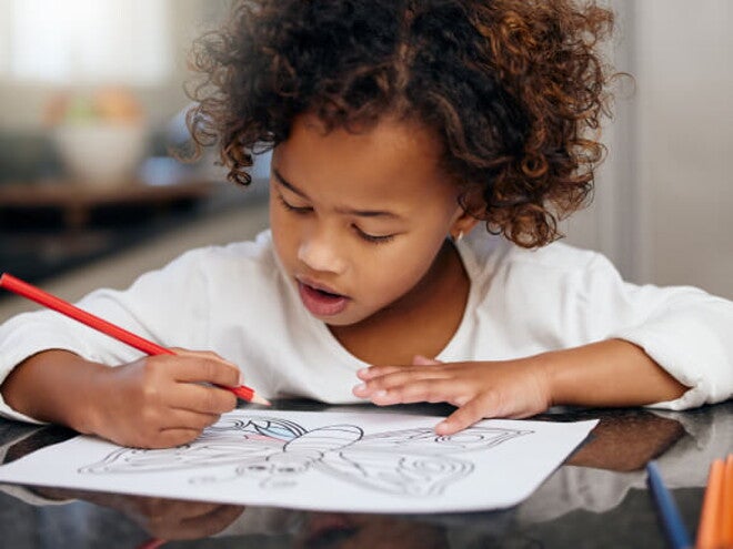 menina debruçada sobre mesa fazendo desenho menina debruçada sobre mesa fazendo desenho