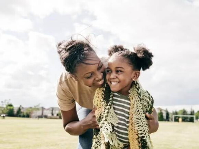 Mãe e filha rindo abraçadas em um campo de futebol Mãe e filha rindo abraçadas em um campo de futebol
