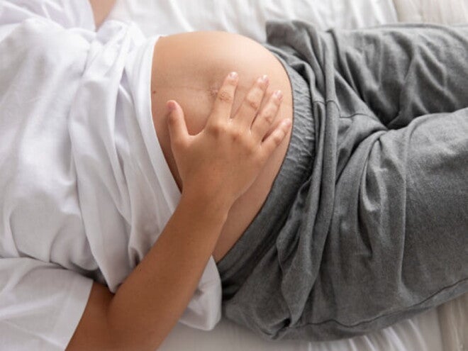 gestante deitada com a mão na barriga proeminente de gestação avançada gestante deitada com a mão na barriga proeminente de gestação avançada
