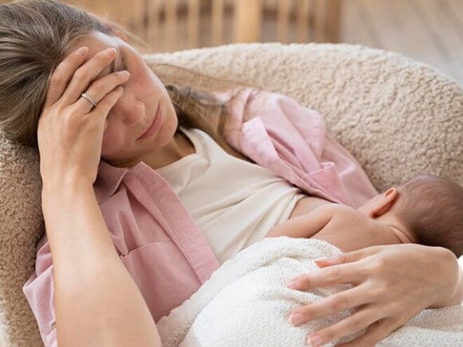 Imagem de uma mãe amamentando seu bebê com a mão na testa e semblante de cansada Imagem de uma mãe amamentando seu bebê com a mão na testa e semblante de cansada