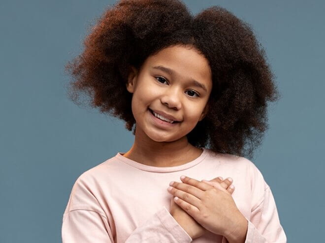 Menina com as duas mãos na região do coração sorrindo Menina com as duas mãos na região do coração sorrindo