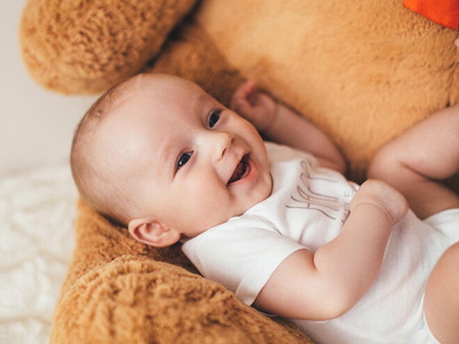 Moleira do bebê: como identificar se está normal, quando fecha e cuidados importantes bebê sorrindo, vestindo body branco