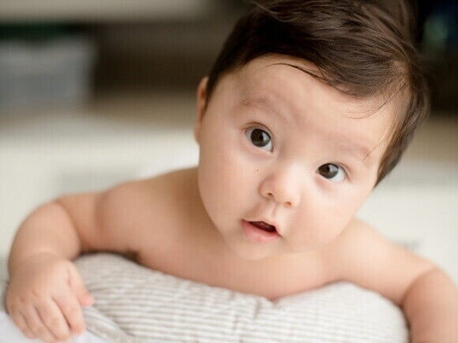 Um bebê deitado olhando de forma atenta com a boca aberta. Um bebê deitado olhando de forma atenta com a boca aberta.