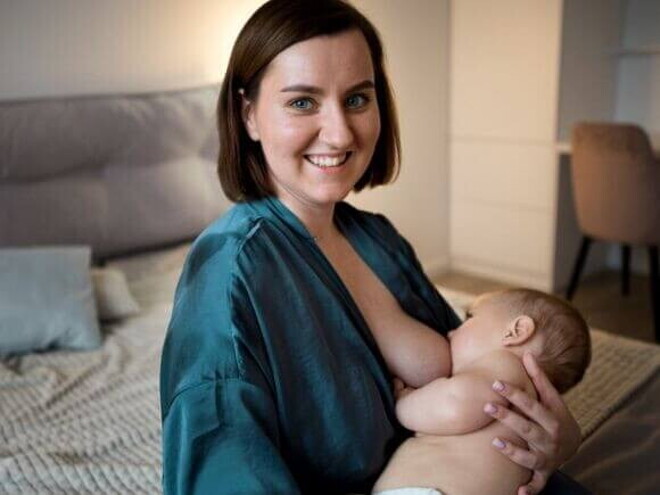 Uma mãe sorrindo, sentada, amamentando um bebê em seu colo Uma mãe sorrindo, sentada, amamentando um bebê em seu colo