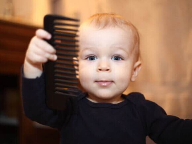 Um bebê segurando um pente de cabelo. Um bebê segurando um pente de cabelo.
