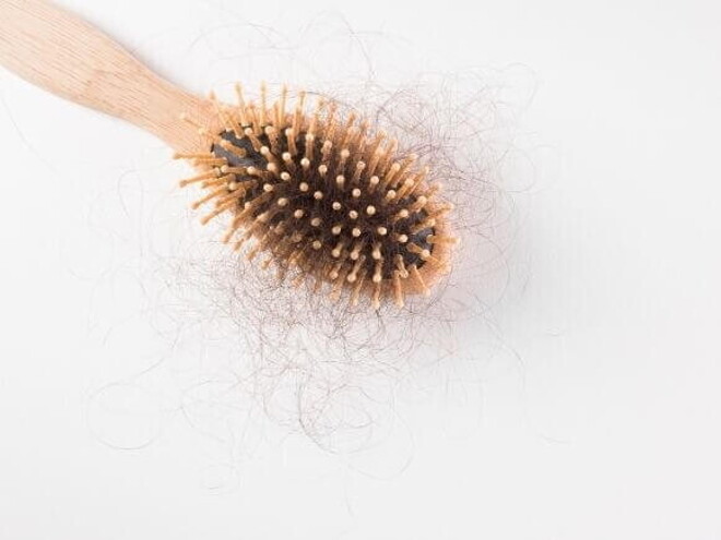 Uma escova de cabelo de madeira, com bastante cabelo preso aos seus dentes, sobre um fundo branco Uma escova de cabelo de madeira, com bastante cabelo preso aos seus dentes, sobre um fundo branco