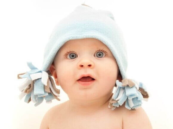 Um bebê com olhar surpreso e boca aberta, vestindo uma touca, sobre um fundo branco Um bebê com olhar surpreso e boca aberta, vestindo uma touca, sobre um fundo branco