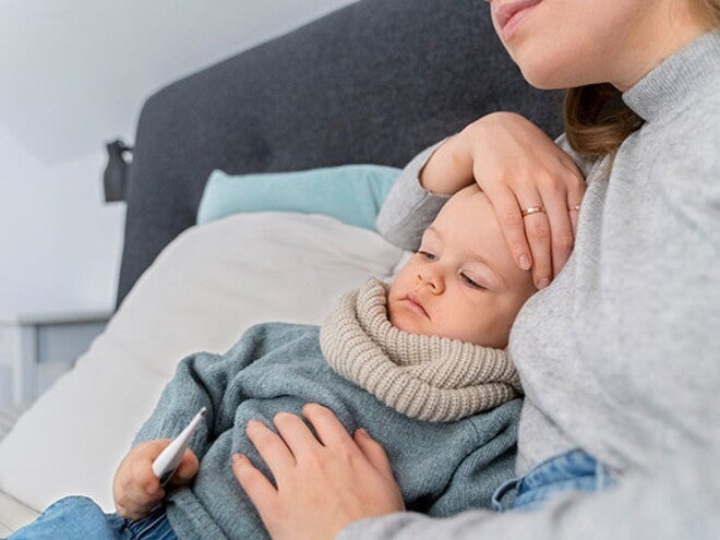 Verme infantil: sintomas, tratamento e prevenção menino sentado enquanto mulher coloca mão sobre a testa para medir temperatura