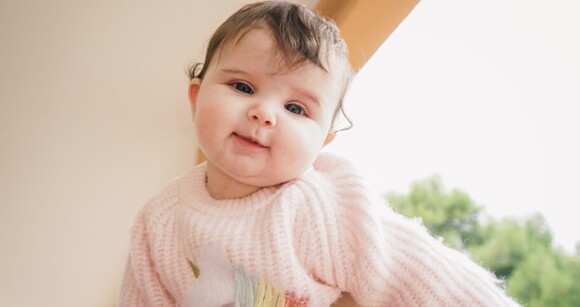 Bebê de olhos claros usando roupa de frio no colo da mãe. Bebê de olhos claros usando roupa de frio no colo da mãe.