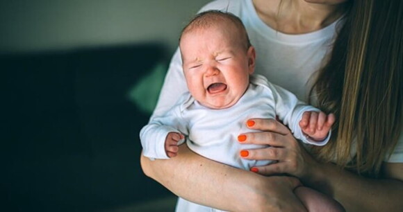 bebê chorando no colo de uma mulher