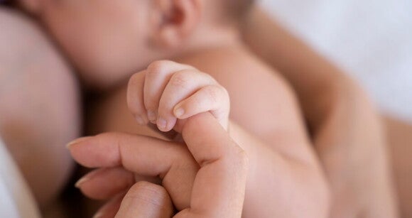 bebê segurando o dedo da mãe enquanto amamenta bebê segurando o dedo da mãe enquanto amamenta