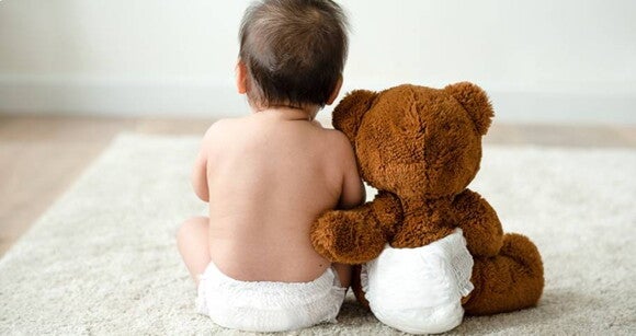 bebê sentado de costas ao lado de um urso de pelúcia bebê sentado de costas ao lado de um urso de pelúcia
