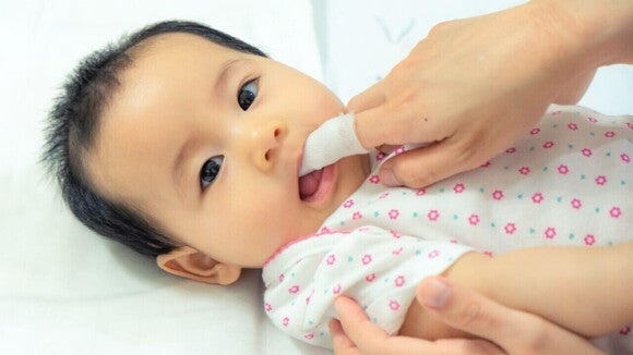 Bebê japonês olhando fixamente para a câmera, enquanto alguém higieniza sua boca. Bebê japonês olhando fixamente para a câmera, enquanto alguém higieniza sua boca.