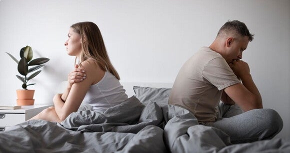 Casal sentados na cama de costas um para o outro. Casal sentados na cama de costas um para o outro.