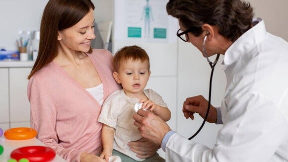 Mãe leva bebê para consulta com pediatra; o médico examina a criança com estetoscópio em ambiente de consultório. Mãe leva bebê para consulta com pediatra; o médico examina a criança com estetoscópio em ambiente de consultório.