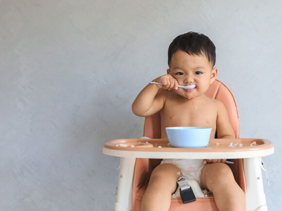 Foto de bebe comendo em cadeira alta.