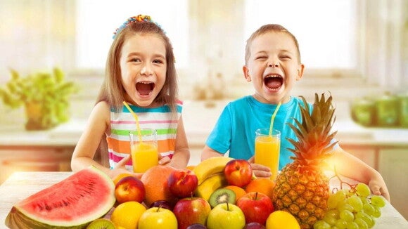 Duas crianças sentadas à mesa, cercadas por uma grande variedade de frutas, em um ambiente claro e arejado. Duas crianças sentadas à mesa, cercadas por uma grande variedade de frutas, em um ambiente claro e arejado.