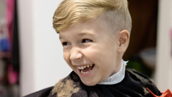 Um menino em um salão de cabeleireiro sorrindo Um menino em um salão de cabeleireiro sorrindo