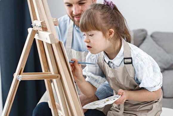 Criança com síndrome de down em uma aula de pintura Criança com síndrome de down em uma aula de pintura