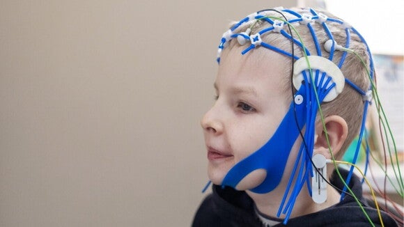 Um menino usando um capacete de EEG com eletrodos presos à sua cabeça. Um menino usando um capacete de EEG com eletrodos presos à sua cabeça.