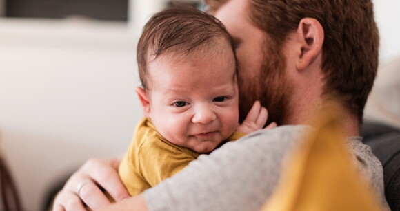 Homem embalando suavemente um bebê nos braços, mostrando o vínculo entre pai e filho Homem embalando suavemente um bebê nos braços, mostrando o vínculo entre pai e filho