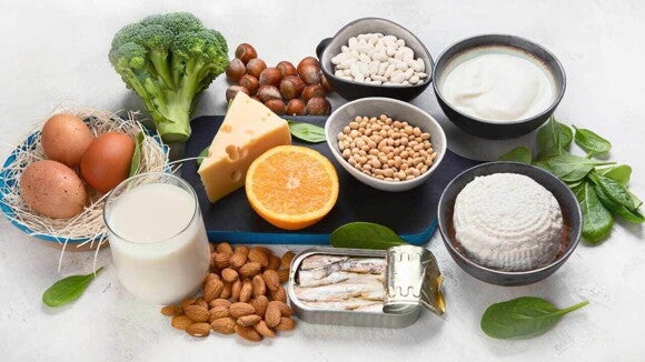 Foto de alimentos ricos em cálcio, reunindo laticínios, ovos, brócolis, nozes, feijões, sardinhas, espinafre e uma laranja Foto de alimentos ricos em cálcio, reunindo laticínios, ovos, brócolis, nozes, feijões, sardinhas, espinafre e uma laranja