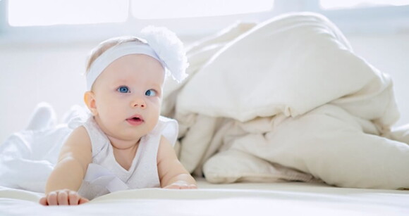 Imagem de bebê com estrabismo em cima da cama. Imagem de bebê com estrabismo em cima da cama.
