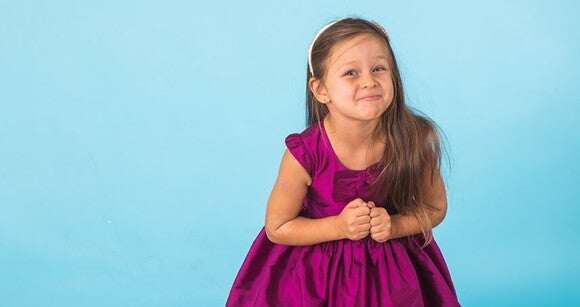Menina usando vestido de princesa e tiara clara em frente a um fundo azul claro Menina usando vestido de princesa e tiara clara em frente a um fundo azul claro