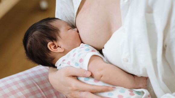 Um bebê recém-nascido deitado no colo de uma mulher sendo amamentado. Um bebê recém-nascido deitado no colo de uma mulher sendo amamentado.