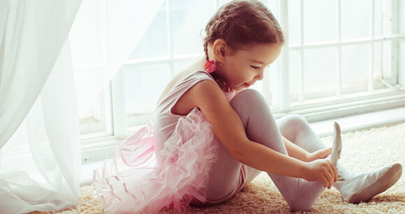 Menina com roupa de bailarina vestindo a sapatilha Menina com roupa de bailarina vestindo a sapatilha