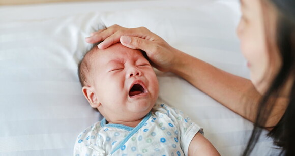 mãe acariciando bebê enquanto ele chora